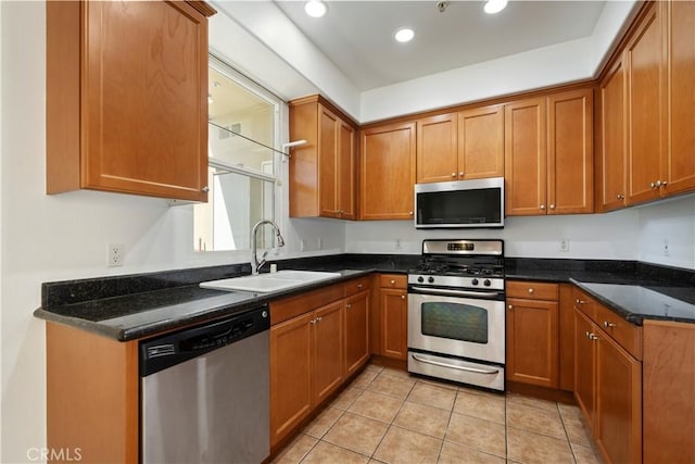 kitchen featuring light tile patterned flooring, appliances with stainless steel finishes, dark stone counters, and sink