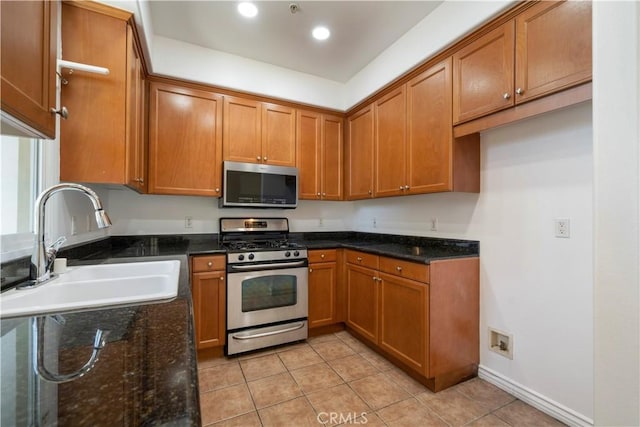 kitchen featuring light tile patterned floors, sink, appliances with stainless steel finishes, and dark stone counters