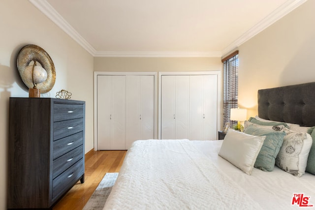 bedroom with crown molding, multiple closets, and hardwood / wood-style floors