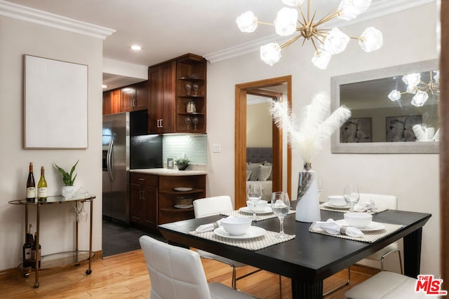 dining room featuring a notable chandelier, ornamental molding, and light wood-type flooring