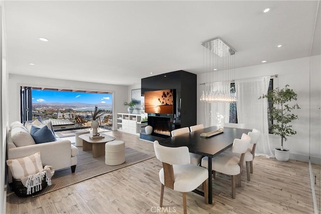 dining space with a large fireplace and light hardwood / wood-style flooring