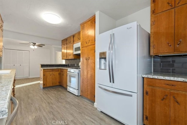 kitchen with white appliances, sink, decorative backsplash, ceiling fan, and light hardwood / wood-style floors