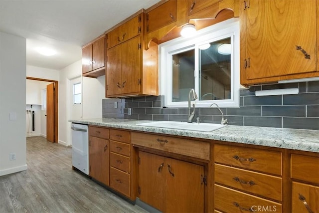 kitchen featuring white dishwasher, decorative backsplash, sink, and light hardwood / wood-style flooring