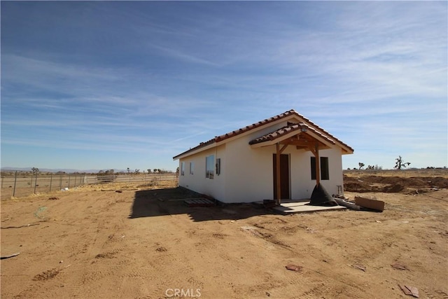 view of front of property with a tiled roof, fence, and stucco siding