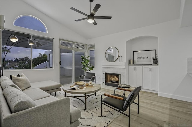 living room with a fireplace, light hardwood / wood-style flooring, ceiling fan, and lofted ceiling