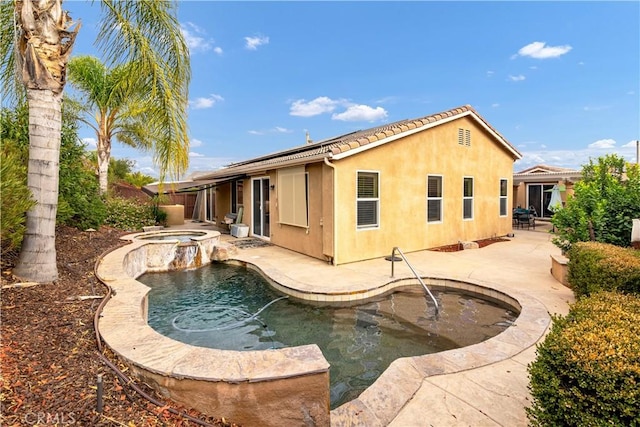 back of house featuring an outdoor pool, a patio, an in ground hot tub, roof mounted solar panels, and stucco siding