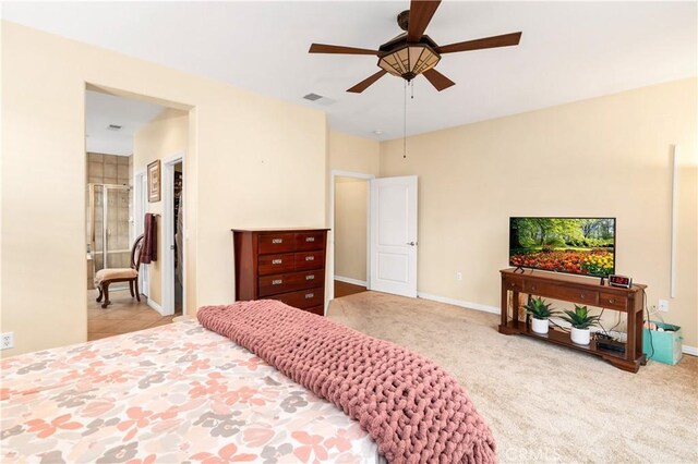 bedroom featuring light carpet, ensuite bathroom, and ceiling fan