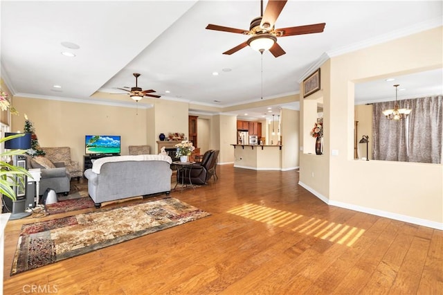 living area with baseboards, ornamental molding, wood finished floors, ceiling fan with notable chandelier, and recessed lighting