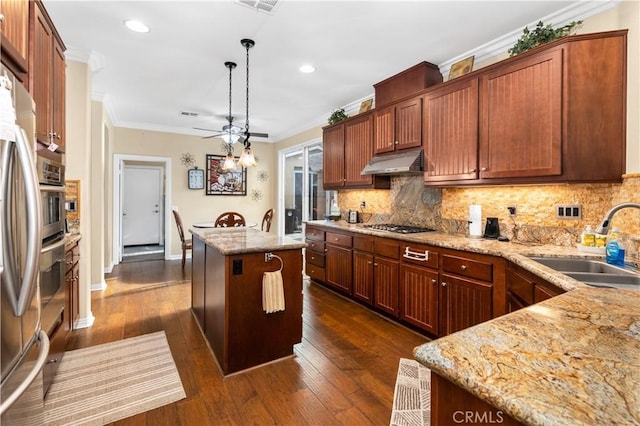 kitchen with a center island, backsplash, ornamental molding, a sink, and under cabinet range hood