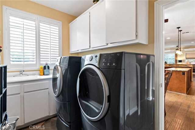 laundry room featuring washing machine and dryer, cabinets, sink, and dark wood-type flooring