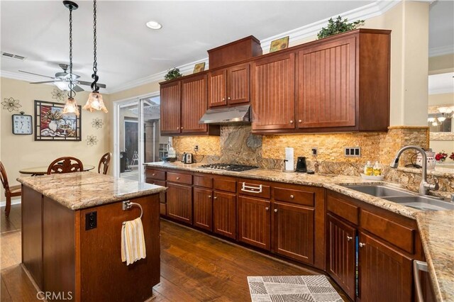 kitchen featuring dark hardwood / wood-style flooring, ornamental molding, sink, hanging light fixtures, and stainless steel gas stovetop