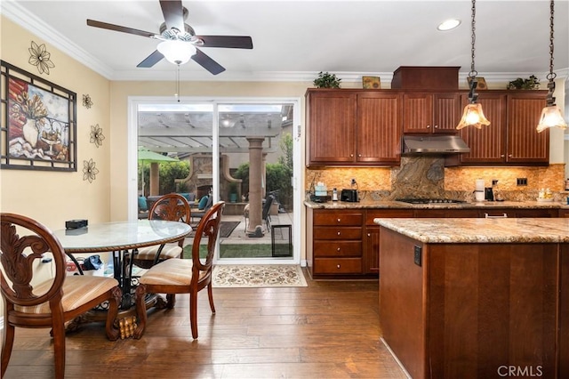 kitchen featuring crown molding, dark hardwood / wood-style floors, light stone countertops, tasteful backsplash, and decorative light fixtures