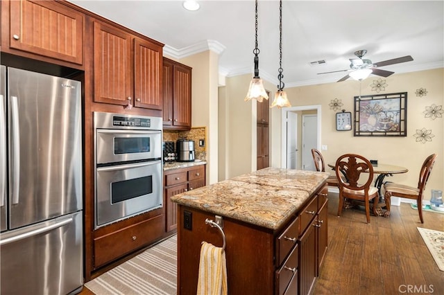 kitchen with appliances with stainless steel finishes, dark hardwood / wood-style flooring, a kitchen island, and crown molding