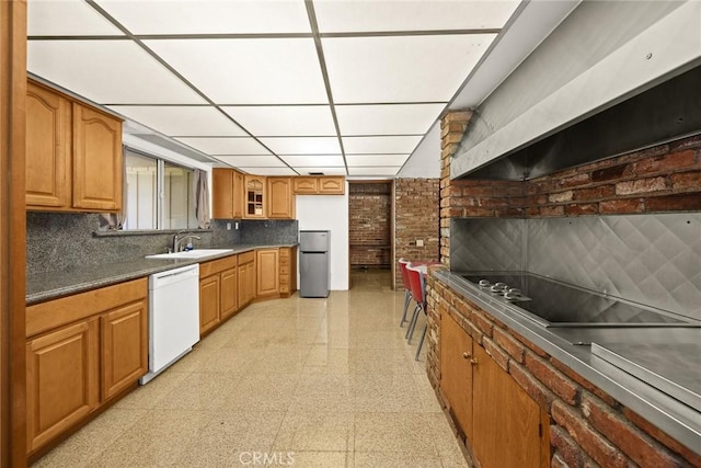 kitchen featuring stainless steel refrigerator, dishwasher, a drop ceiling, sink, and extractor fan