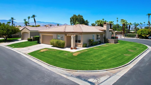 view of front facade featuring a garage, a mountain view, and a front lawn