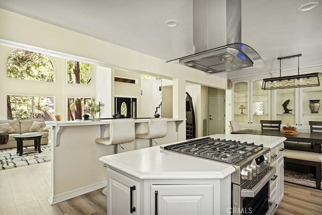 28670 Shenandoah Dr, Lake Arrowhead, CA 92352 - kitchen with stainless steel range with gas stovetop, island range hood, open floor plan, a kitchen island, and light wood-style floors