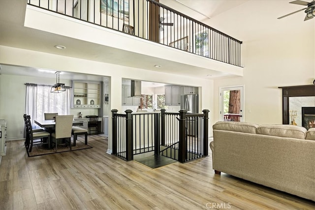 28670 Shenandoah Dr, Lake Arrowhead, CA 92352 - living room with light wood finished floors, plenty of natural light, a high ceiling, a ceiling fan, and a premium fireplace