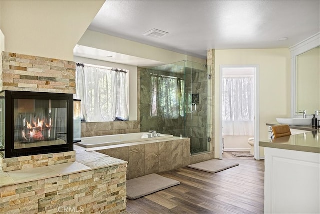 28670 Shenandoah Dr, Lake Arrowhead, CA 92352 - full bathroom featuring vanity, a garden tub, a stall shower, wood finished floors, and a multi sided fireplace