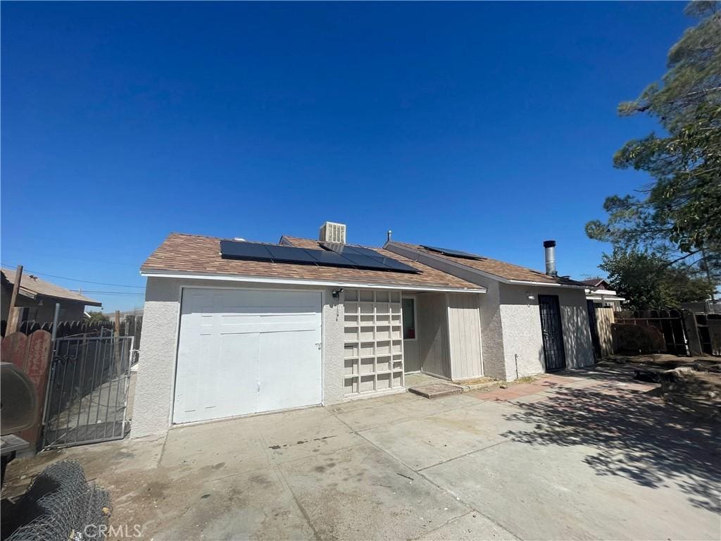 1221 Flora St, Barstow, CA 92311 - view of front facade with a garage and solar panels