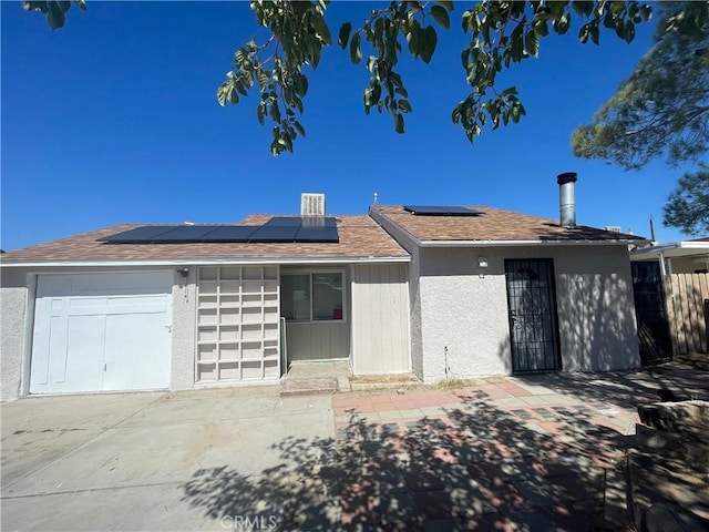 single story home with a garage and solar panels