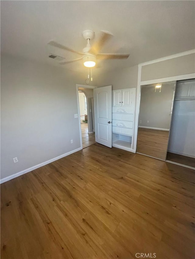 unfurnished bedroom featuring hardwood / wood-style floors, a closet, and ceiling fan