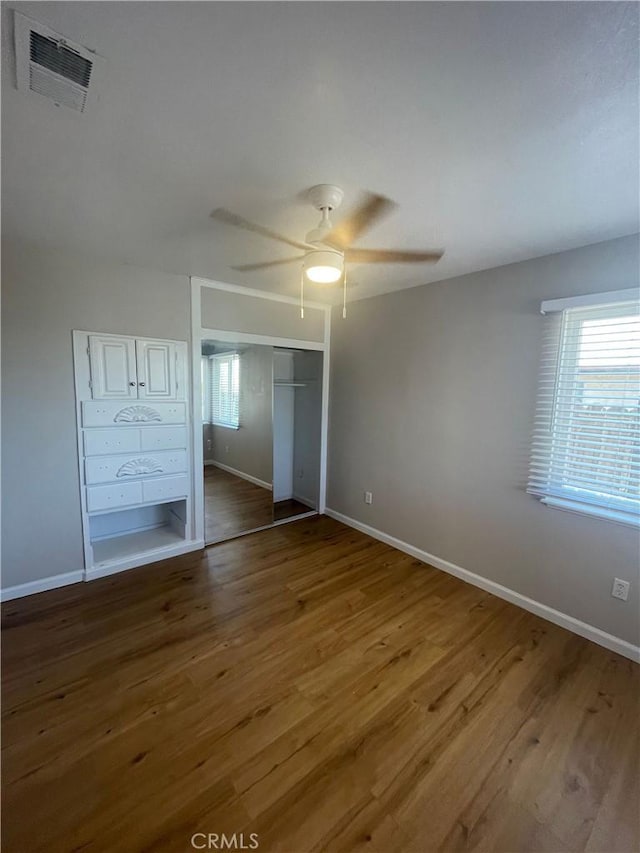 unfurnished bedroom featuring ceiling fan, wood-type flooring, and a closet