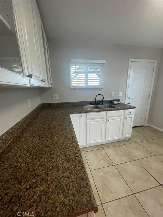 kitchen featuring dark stone counters, white cabinets, sink, light tile patterned flooring, and kitchen peninsula