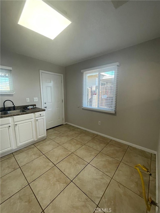 kitchen with white cabinetry, sink, and light tile patterned floors