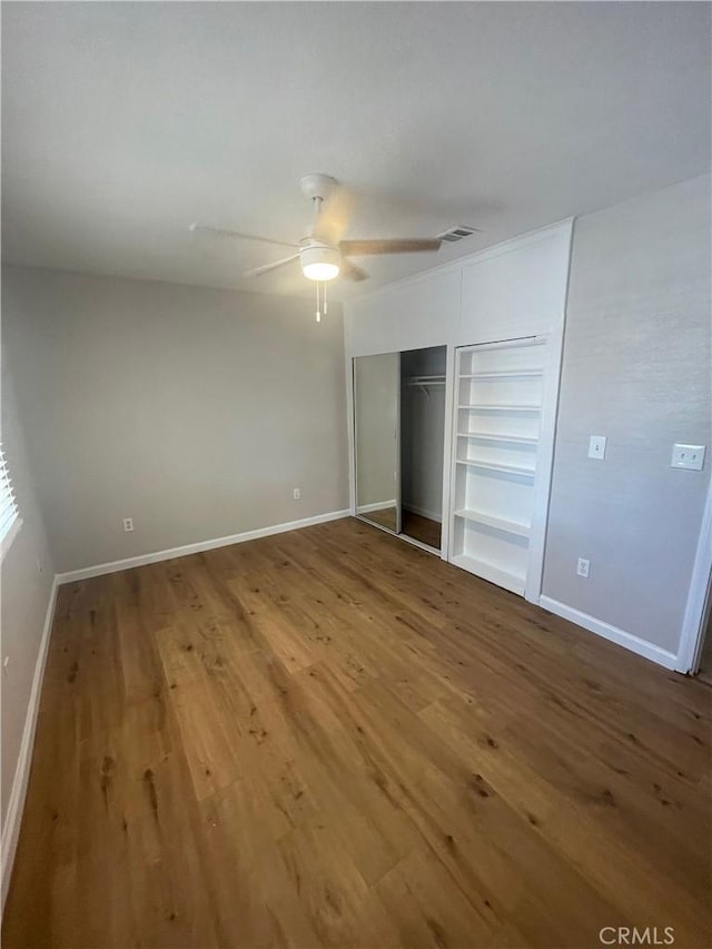 unfurnished bedroom featuring ceiling fan, wood-type flooring, and a closet