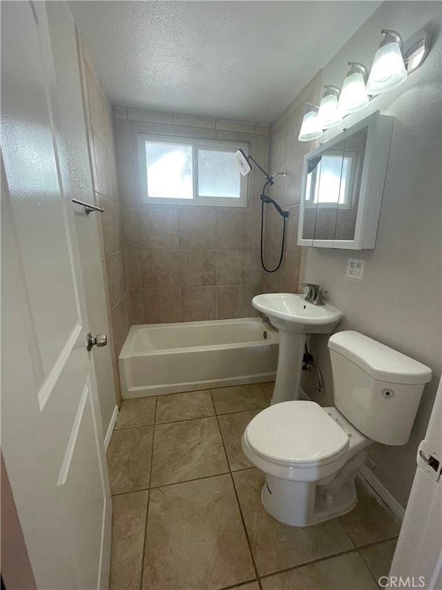 full bathroom featuring tile patterned floors, a textured ceiling, sink, toilet, and tiled shower / bath