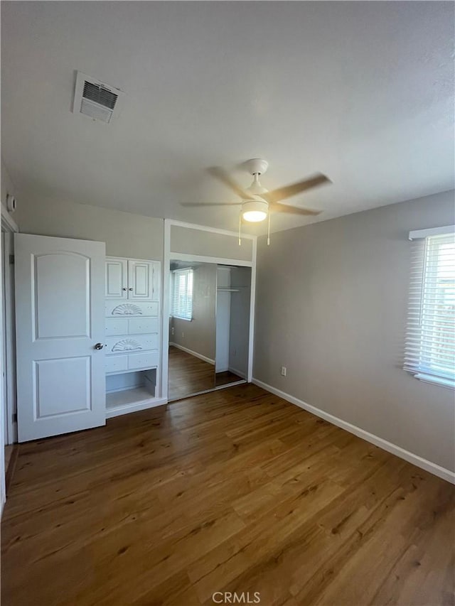 unfurnished bedroom with wood-type flooring, a closet, and ceiling fan