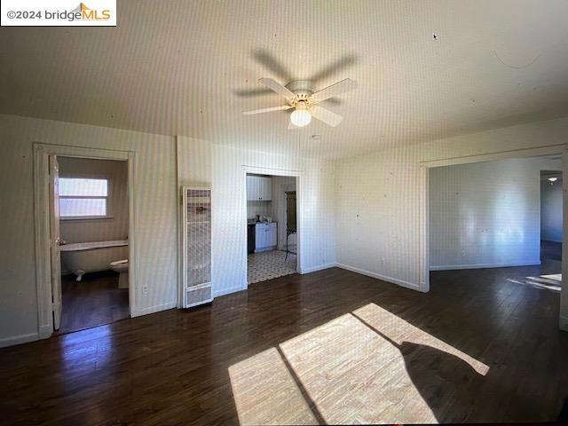 unfurnished living room with dark hardwood / wood-style floors and ceiling fan