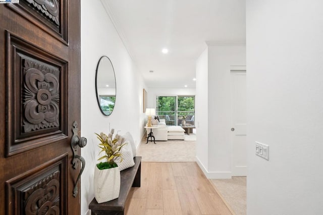 corridor featuring light wood-type flooring and crown molding