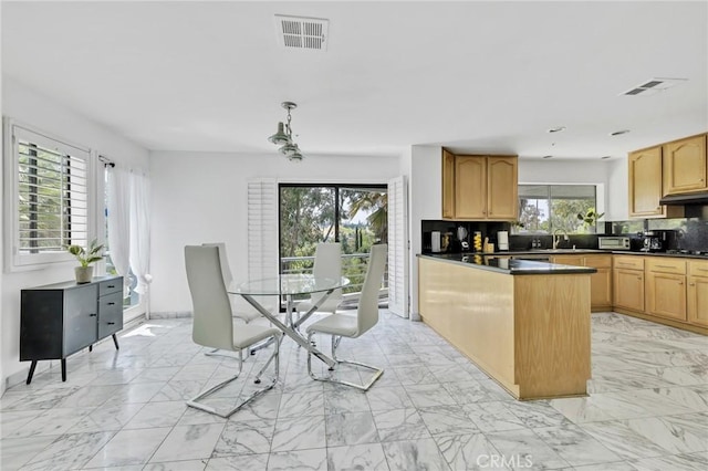 kitchen featuring decorative backsplash, light brown cabinets, decorative light fixtures, and plenty of natural light