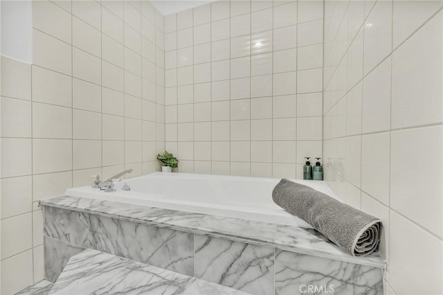 bathroom with tiled tub and tile walls