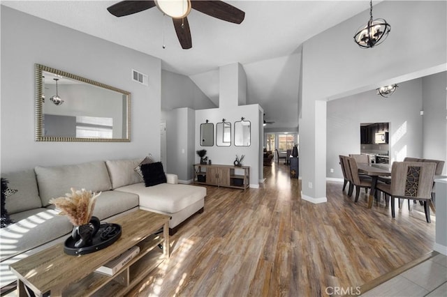 living room featuring hardwood / wood-style floors, high vaulted ceiling, and ceiling fan with notable chandelier