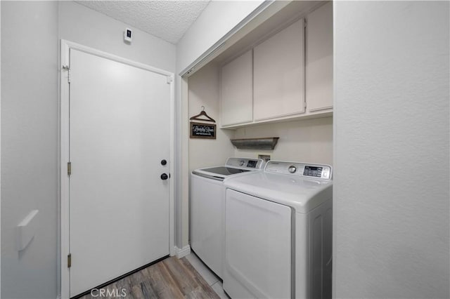 clothes washing area with cabinets, a textured ceiling, light wood-type flooring, and independent washer and dryer