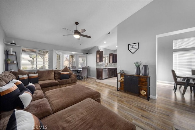 living room with light hardwood / wood-style floors, high vaulted ceiling, and ceiling fan