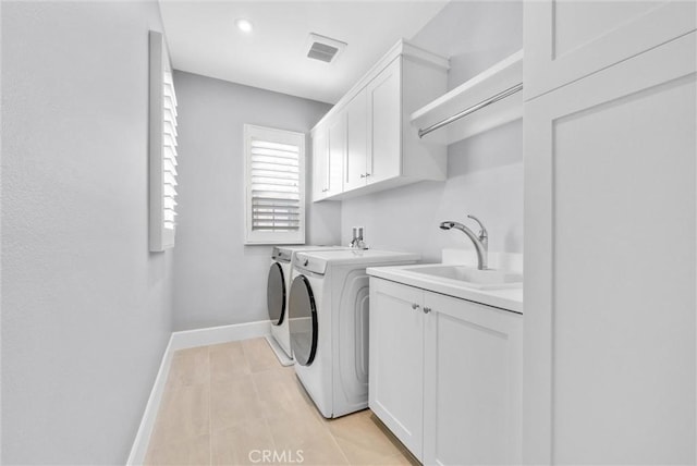 clothes washing area featuring washing machine and dryer, cabinets, and sink