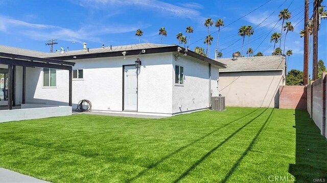 back of property featuring cooling unit and a yard