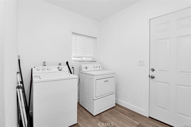 laundry room with washer and clothes dryer and light hardwood / wood-style flooring