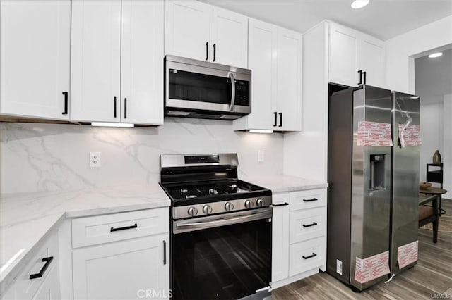 kitchen featuring white cabinets, decorative backsplash, appliances with stainless steel finishes, and dark hardwood / wood-style flooring