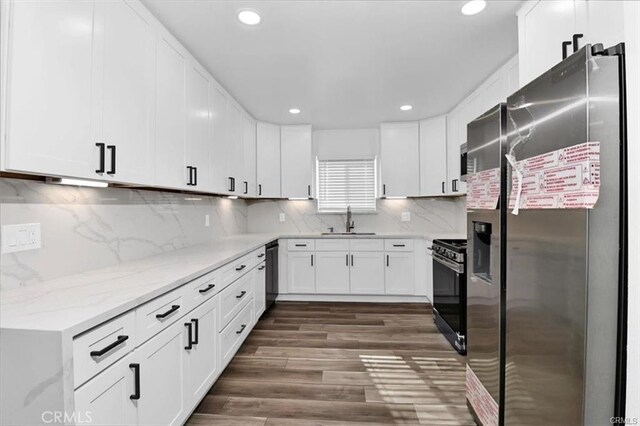 kitchen featuring appliances with stainless steel finishes, decorative backsplash, white cabinets, light stone counters, and sink