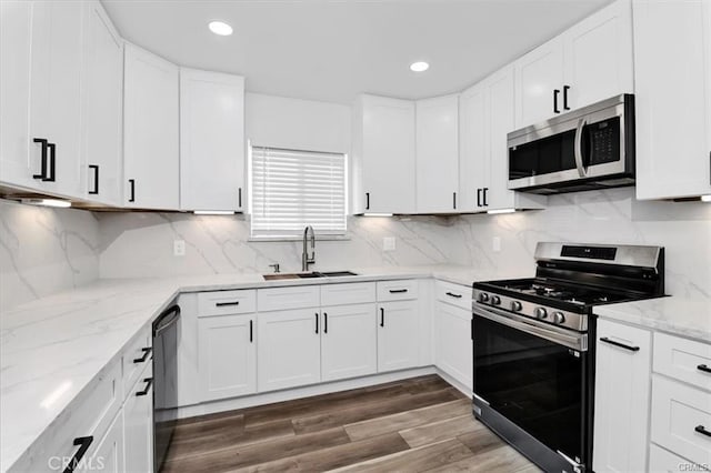 kitchen with stainless steel appliances, backsplash, white cabinets, and sink