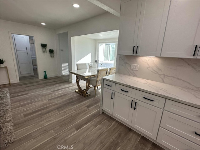 kitchen with hardwood / wood-style floors, decorative backsplash, white cabinets, and light stone counters