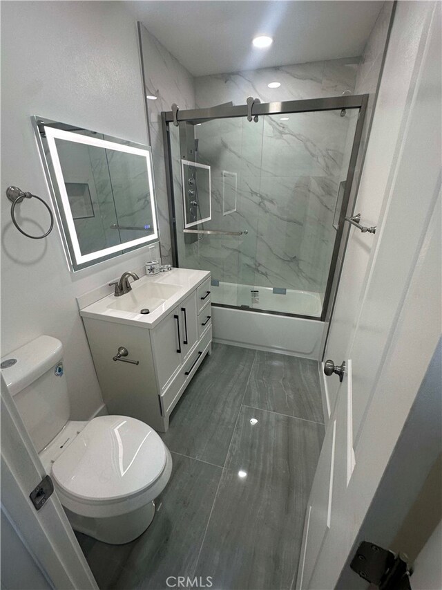 full bathroom featuring toilet, combined bath / shower with glass door, and vanity