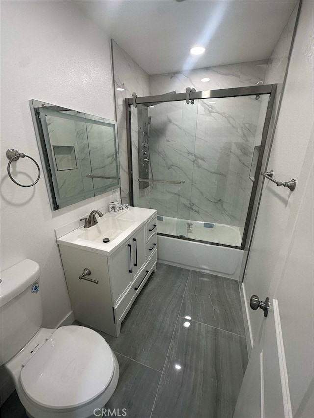 full bathroom featuring toilet, vanity, and shower / bath combination with glass door