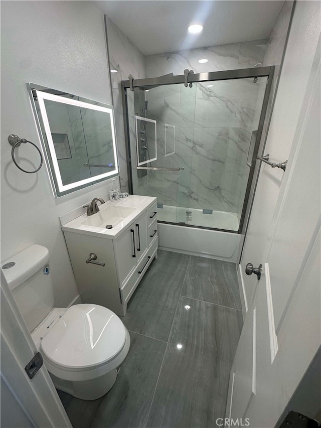 full bathroom with toilet, vanity, and bath / shower combo with glass door