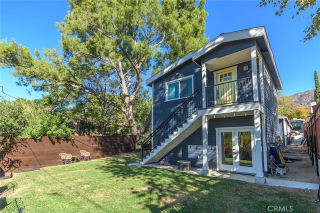 rear view of house with a lawn, french doors, and a balcony