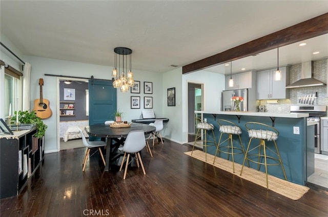 dining room featuring beam ceiling, a barn door, and dark hardwood / wood-style floors